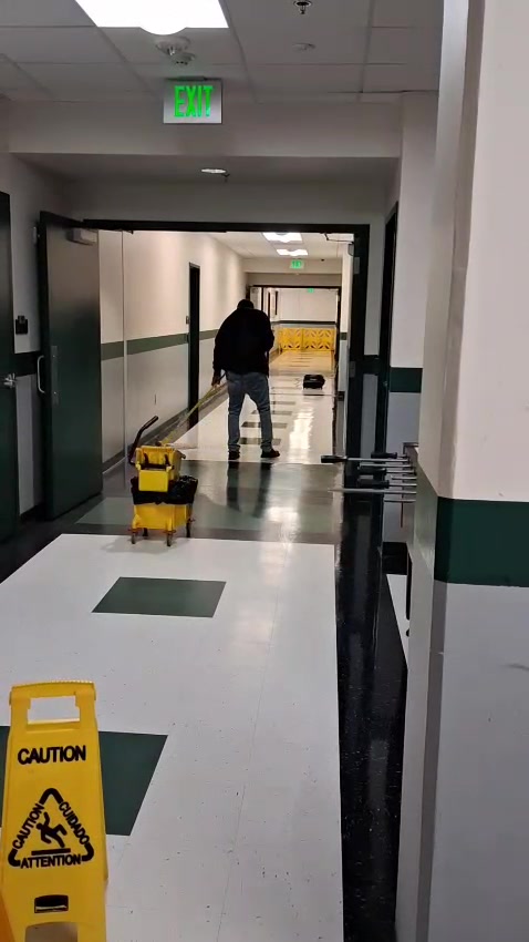 Montoya team member cleaning a corridor floor with caution signs in place
