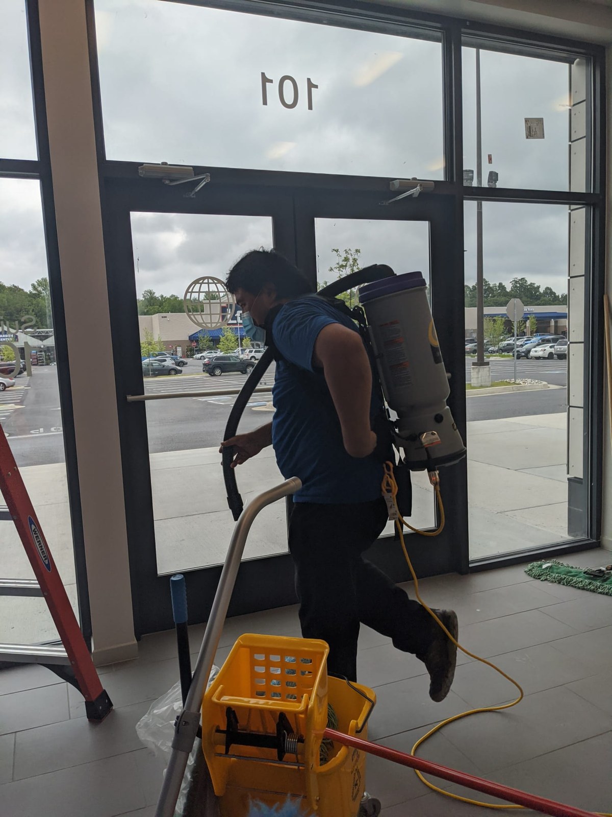 Montoya team member cleaning inside a glass-fronted entrance