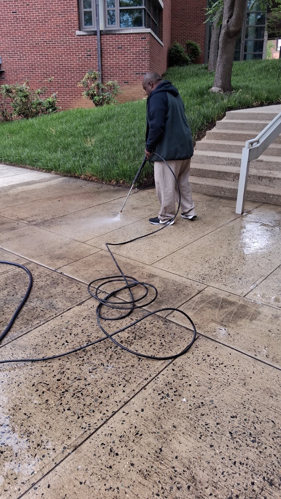 Montoya team member pressure-washing an outdoor walkway